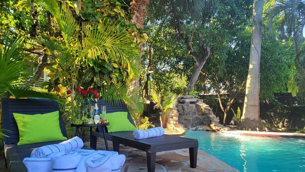 A poolside area with two lounge chairs, a table with drinks, and a basket of towels.