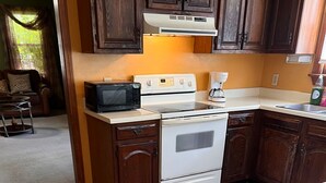 Eine Küche mit Holzausstattung, einem weißen Herd, einer Mikrowelle und einer Kaffeemaschine.
