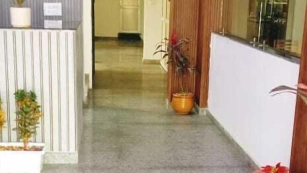 A hallway with a reception desk, potted plants, and a glass partition.