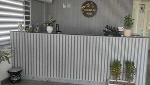 A reception desk with a striped design, a sign reading "Starlight Inn Hotel", and potted plants.