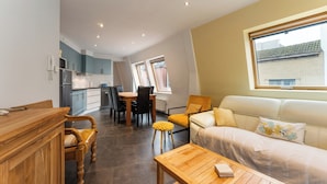 Un espace de vie compact comprenant un coin cuisine, un coin repas et un espace détente avec un canapé et une table basse.