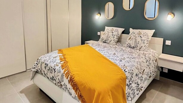 A bedroom with a bed, a nightstand, a mirror, and a wardrobe. - Apartment "Lune" RDC terrace, private parking (Saint-Julien-Chapteuil)