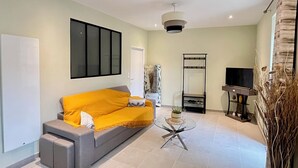 A modern living room with a grey sofa, a glass coffee table, a TV on a stand, and a large mirror. - Apartment "Lune" RDC terrace, private parking (Saint-Julien-Chapteuil)