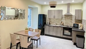 A modern kitchen with a dining area, featuring a large mirror, a built-in stove, and a sink. - Apartment "Lune" RDC terrace, private parking (Saint-Julien-Chapteuil)