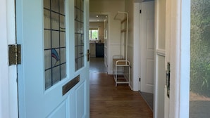 A hallway with a wooden floor, a white door with glass panels, and a hanging light fixture. - Bungalow with distant sea views (Colwyn Bay)