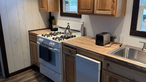 A modern kitchen with wooden cabinets, a gas stove, a dishwasher, and a window providing natural light. - Foothills Lodge 9 Suite - South Fork (South Fork)
