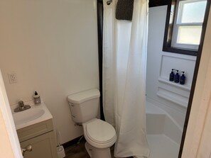 A bathroom with a toilet, sink, and shower curtain.