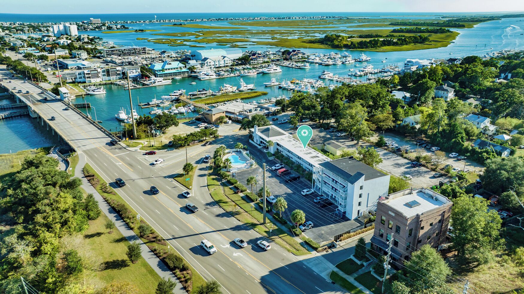 An aerial view of a marina with boats, a parking lot, and buildings.