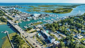 An aerial view of a coastal town with a marina, residential areas, and a bridge connecting to the mainland.