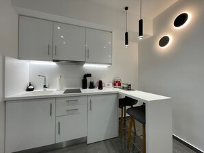 Modern kitchen with a minimalist design, featuring a coffee maker, kettle, and stainless steel range hood.