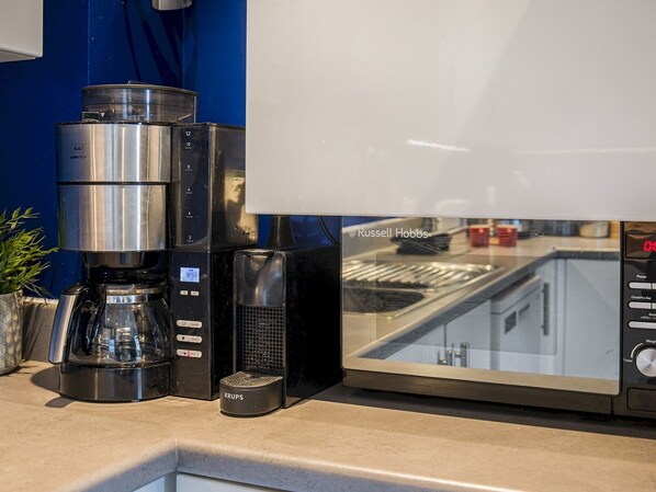 A coffee maker, a Krups scale, and a microwave oven on a kitchen counter.