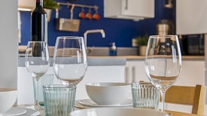 A dining table set with clear glassware and white plates, a wine bottle, and a clock on the wall in the background. - Luxury Loft Living | Free Parking - Pass the Keys (Brighton)