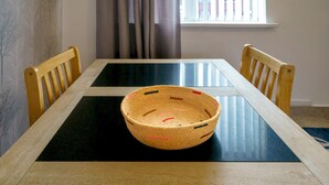 A dining table with a woven basket in the center, surrounded by wooden chairs.