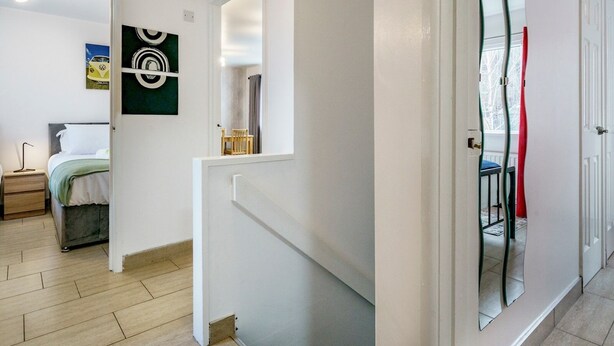 A modern hotel room with a bed, a desk, and a chair. There is a bathroom visible through a glass door.