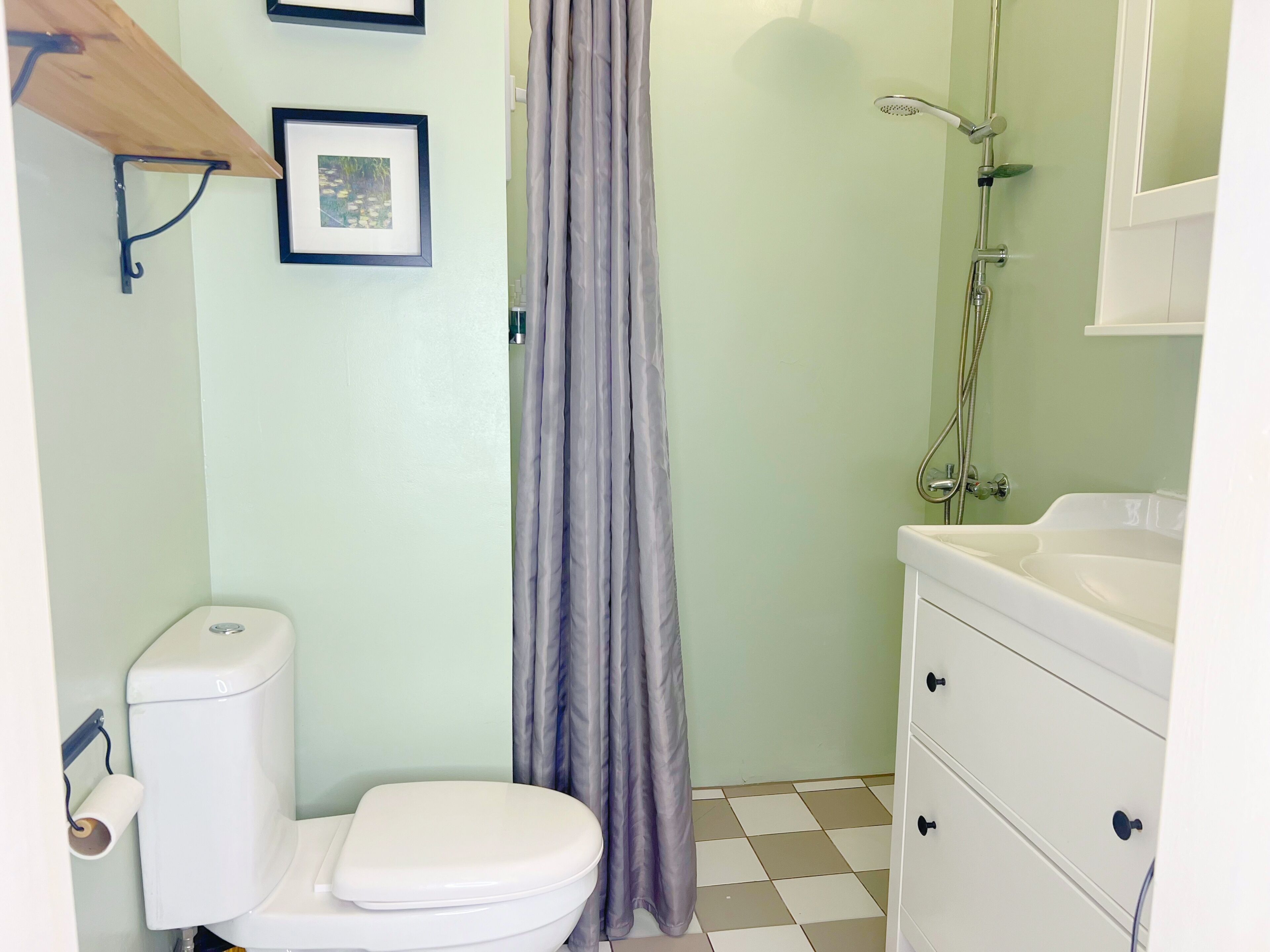 A bathroom with a toilet, a shower, and a sink.