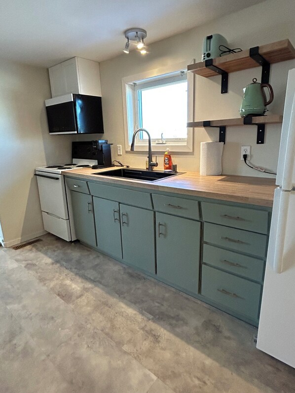 A kitchen with a built-in stove, a sink, and a window above the counter.
