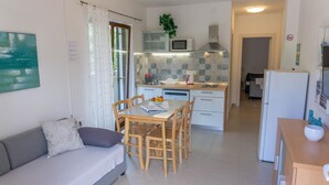 A compact living space with a dining area, kitchenette, and a sofa. - Apartment Adria Nr. 2 with garden and grill (Baska)