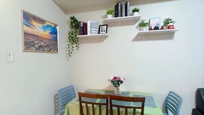 A dining area with a table set for four, surrounded by chairs, and shelves above holding books and decorative items. - Stunning Mall of Asia View @ Shell Residences (Pasay)