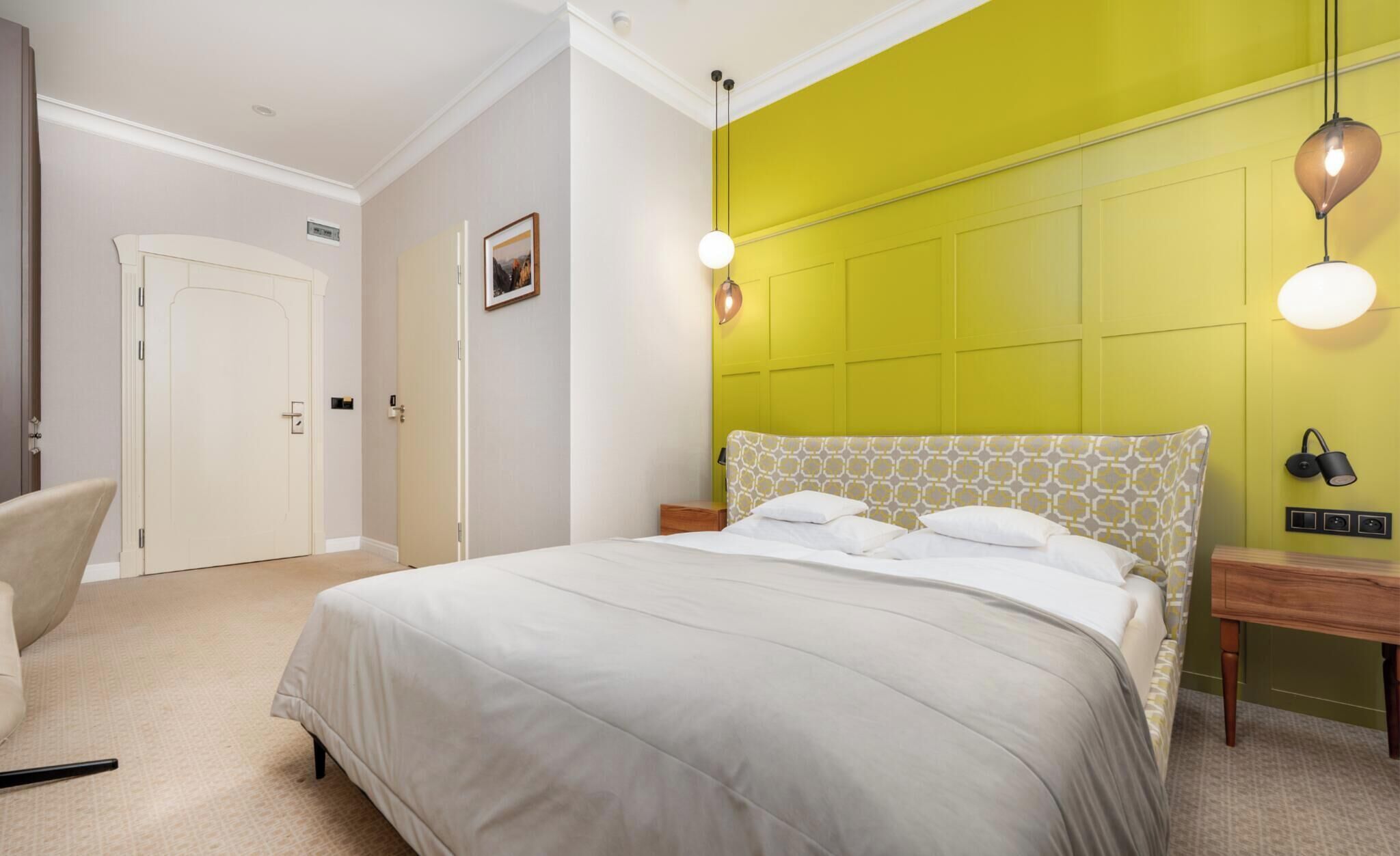 A bedroom with a bed, bedside tables, a chair, and a door.