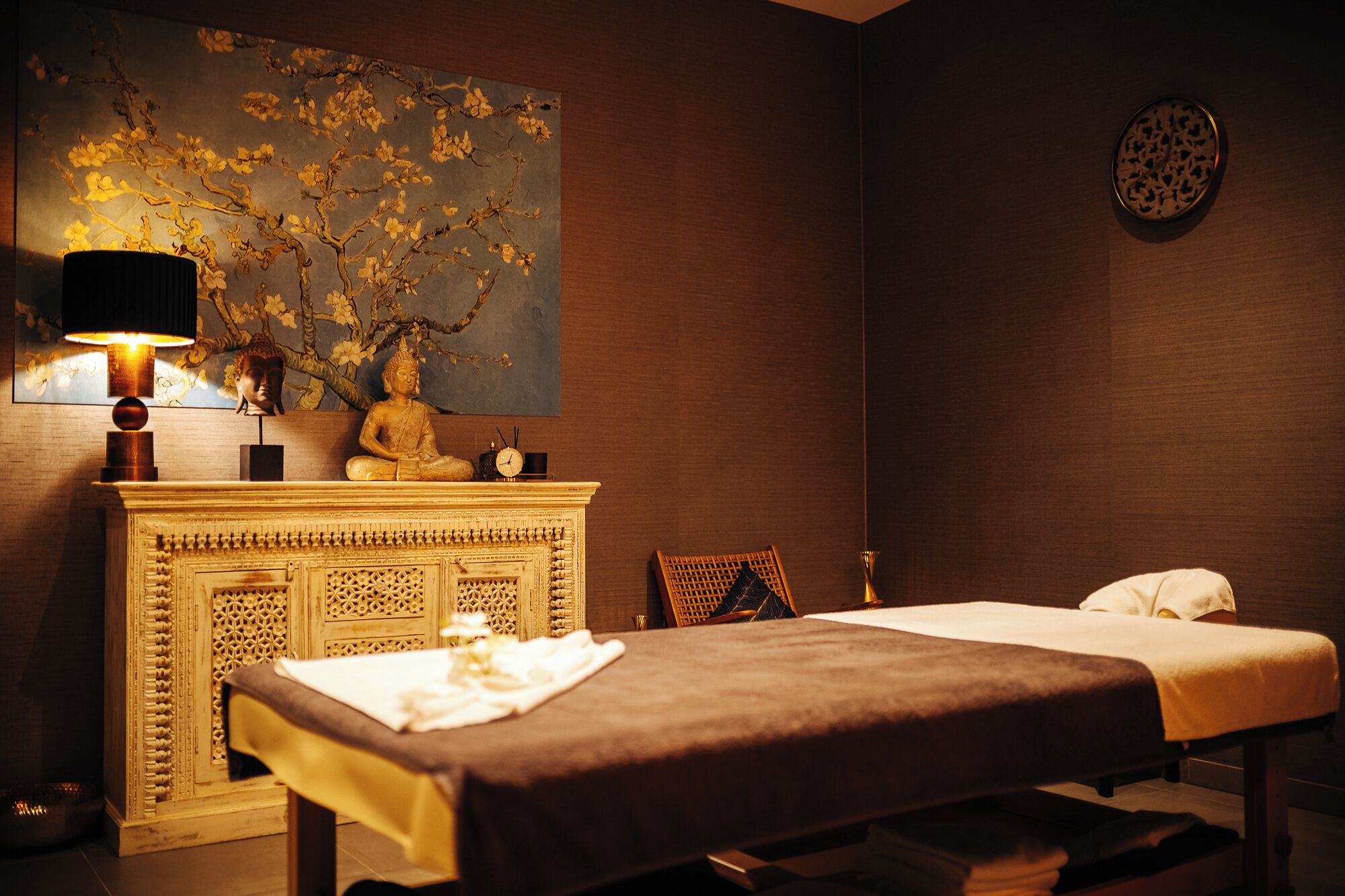 Une pièce comprenant une table de massage, une statue de Bouddha, une horloge et un élément décoratif mural.