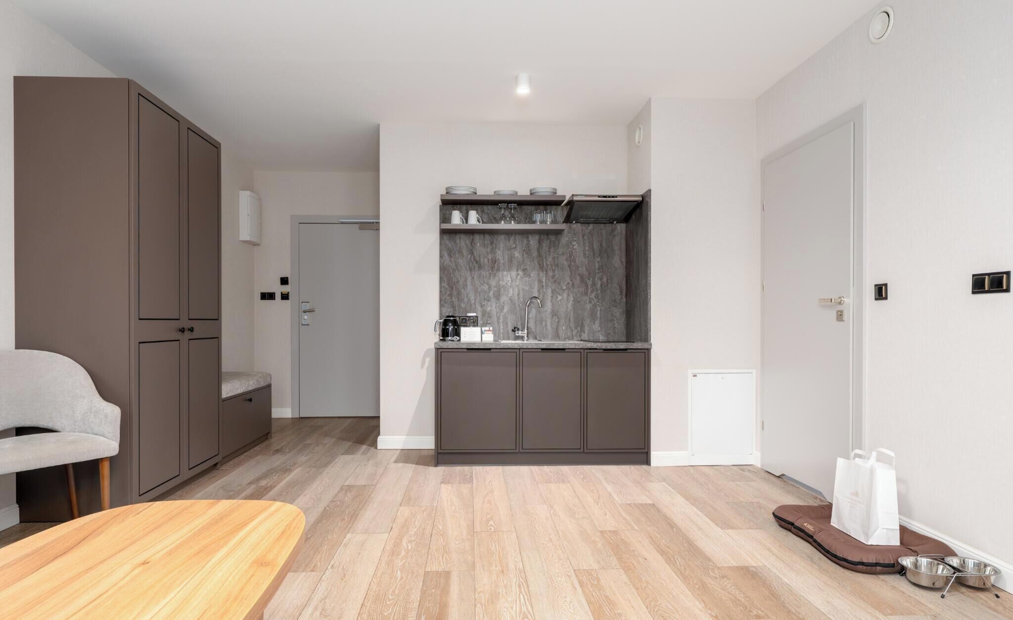 A modern, compact living space with a kitchenette, a seating area, and a door leading to another room.