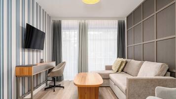 A modern living room with a flat-screen TV, a wooden coffee table, a sofa, and a desk with a chair.