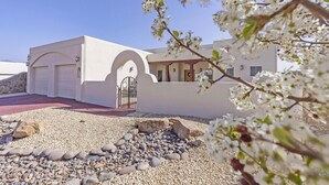 A white building with a driveway, a garage, and a small garden area with pebbles and rocks.