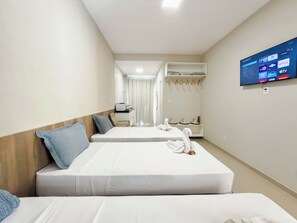 Una habitación de hotel con dos camas, un televisor mostrando un servicio de streaming y un baño al fondo.