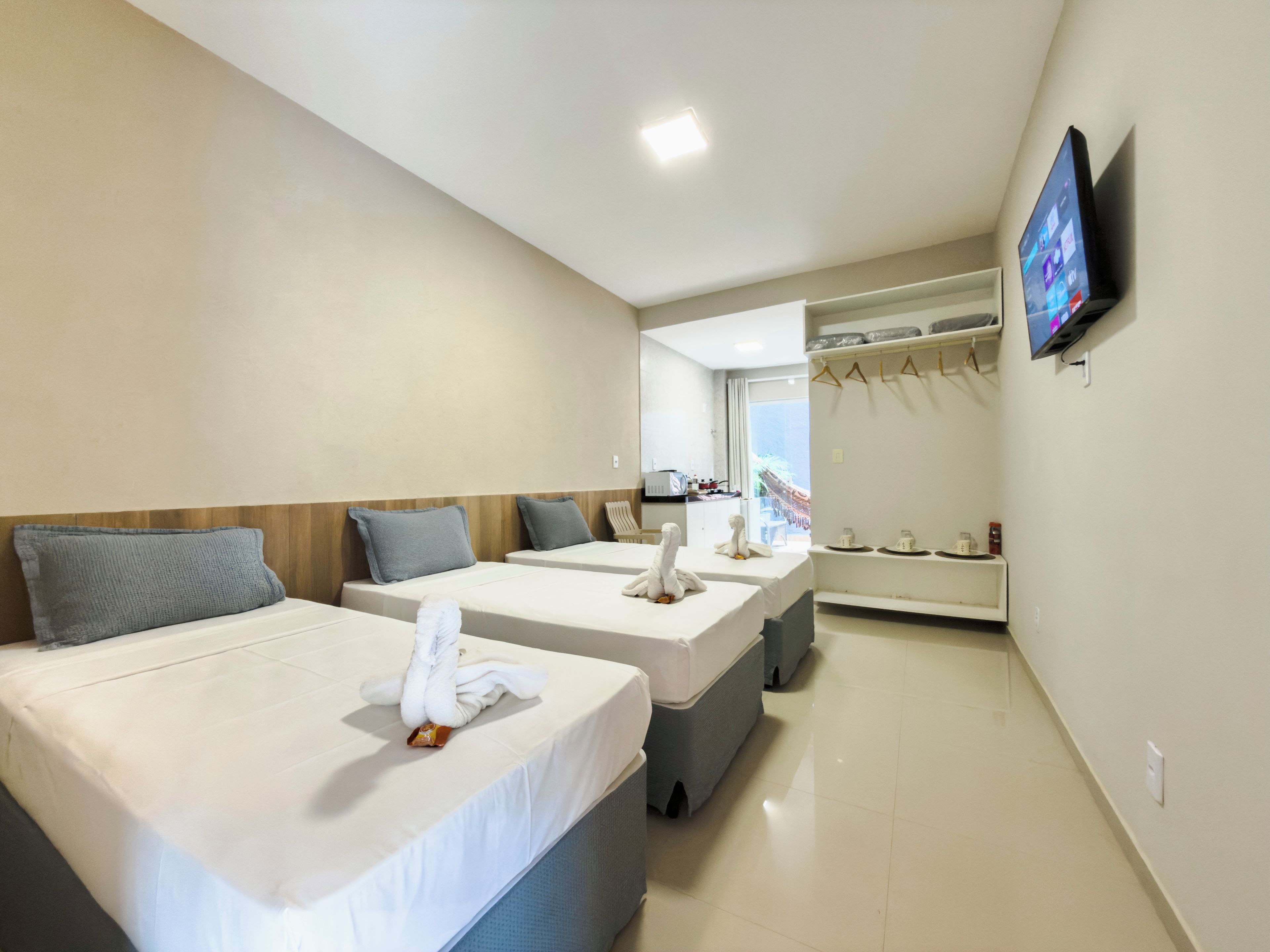 Quarto de hotel com duas camas, uma televisão fixada na parede e vista para o mar pela janela.