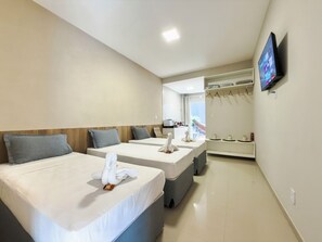 Une chambre d’hôtel avec deux lits, un téléviseur fixé au mur et une vue sur la mer par la fenêtre.