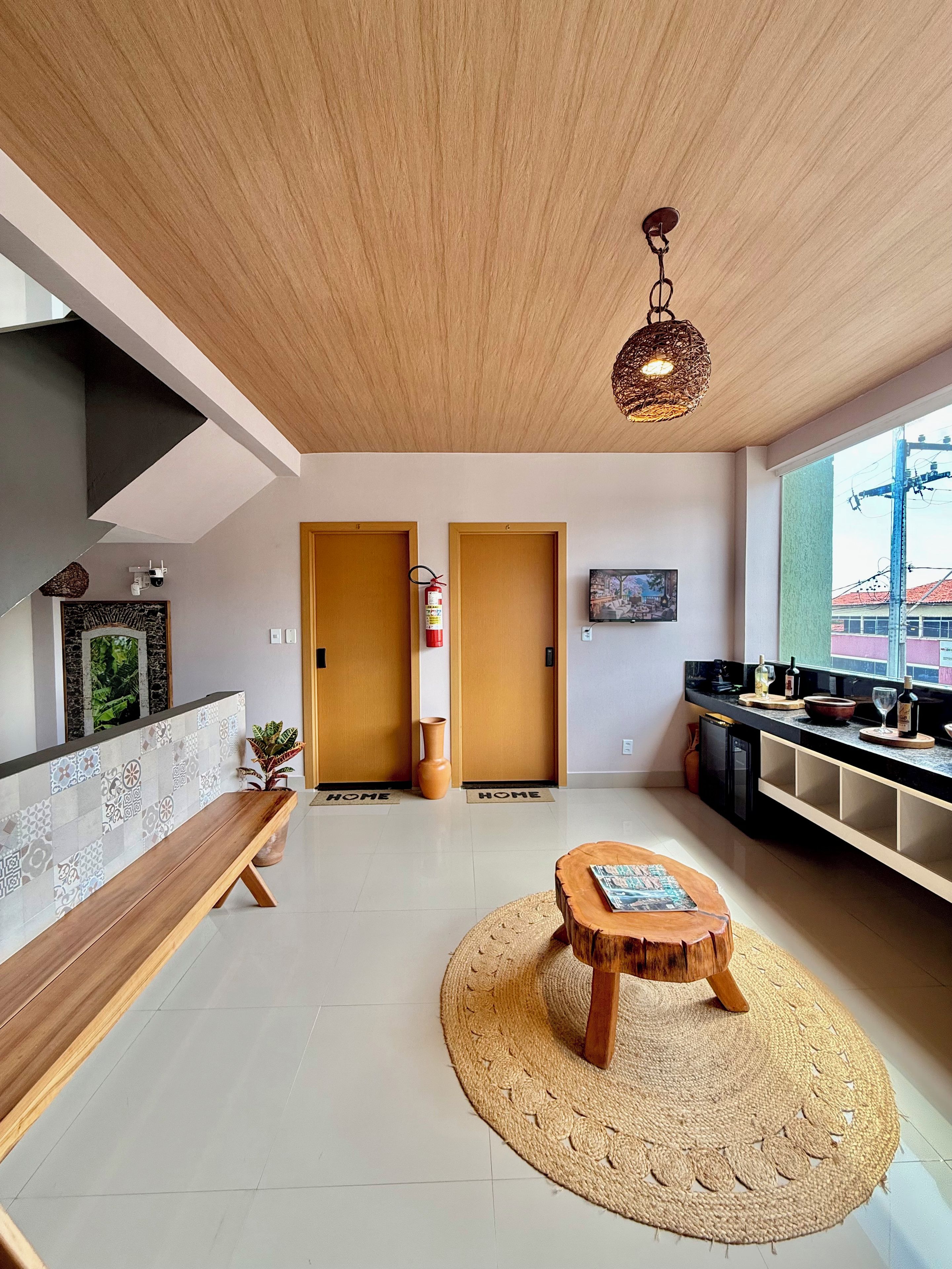 Una sala moderna con un banco de madera, una mesa de centro redonda y un ventanal con vistas a edificios.