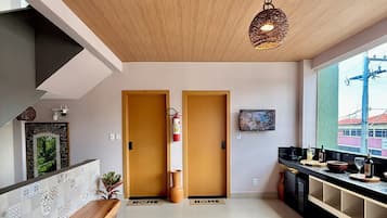 Una sala moderna con un banco de madera, una mesa de centro redonda y un ventanal con vistas a edificios.