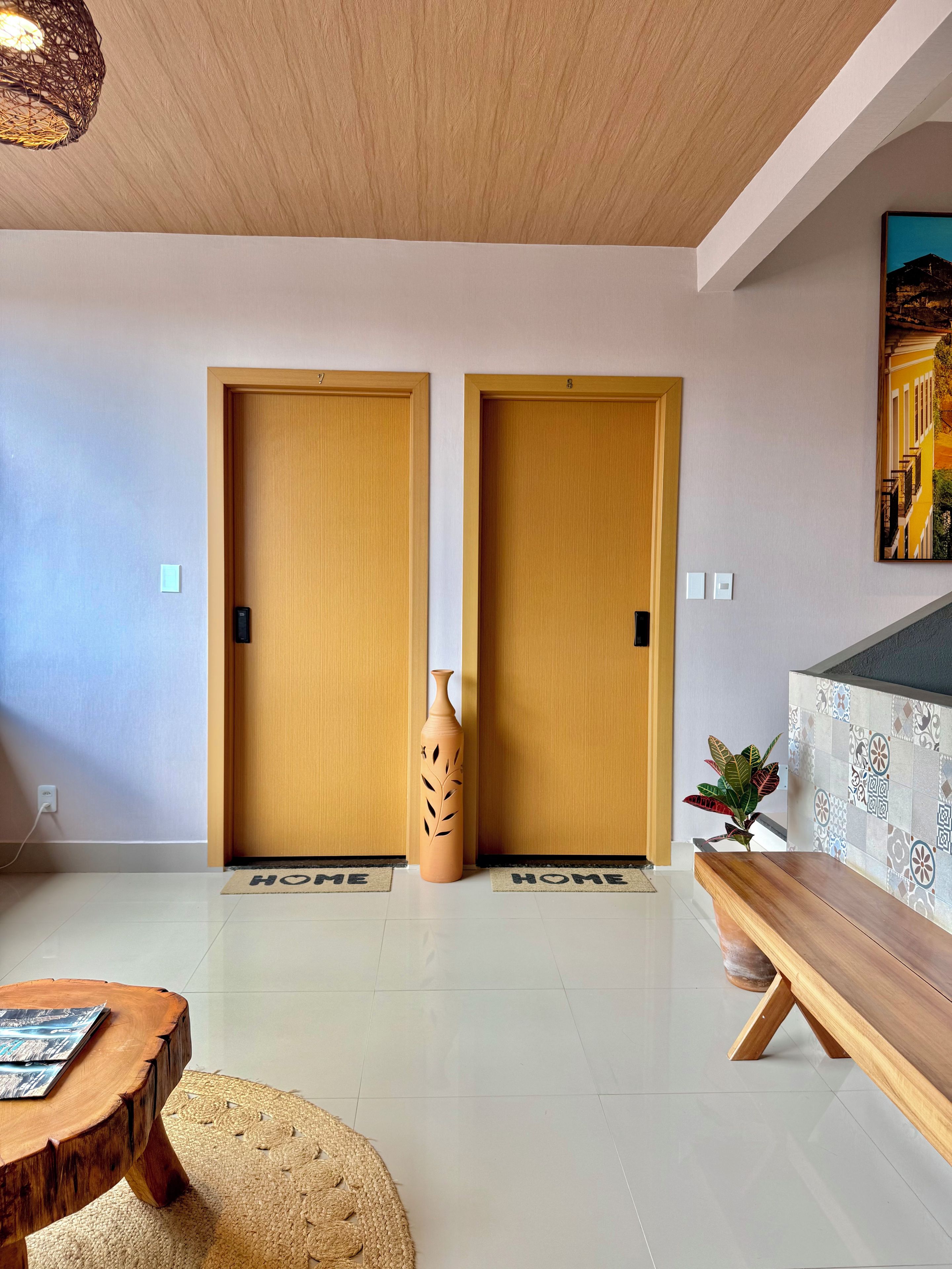 A modern interior with two wooden doors, a vase, a bench, and a patterned wall.