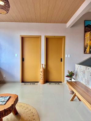 Un intérieur moderne avec deux portes en bois, un vase, un banc et un mur orné de motifs.