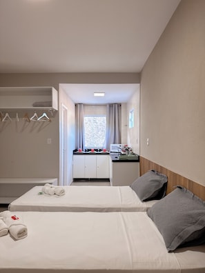 Une chambre d’hôtel avec deux lits, une kitchenette, une salle de bain et une vue sur l’extérieur.