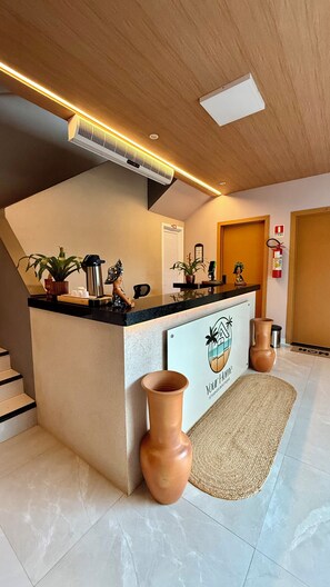 Un espace d’accueil comprenant un comptoir, un extincteur, une plante en pot, un vase et un panneau indiquant : « Your Home Studios Boutique ».