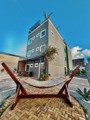 Ein modernes Gebäude mit flachem Dach, zahlreichen Fenstern und einer kleinen Gartenanlage mit einer Hängematte.