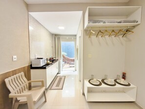 Une cuisine moderne équipée d’un four à micro-ondes, d’une cuisinière et de placards. On y trouve un banc et une petite table avec des assiettes et des tasses. Un couloir mène à un balcon avec vue.