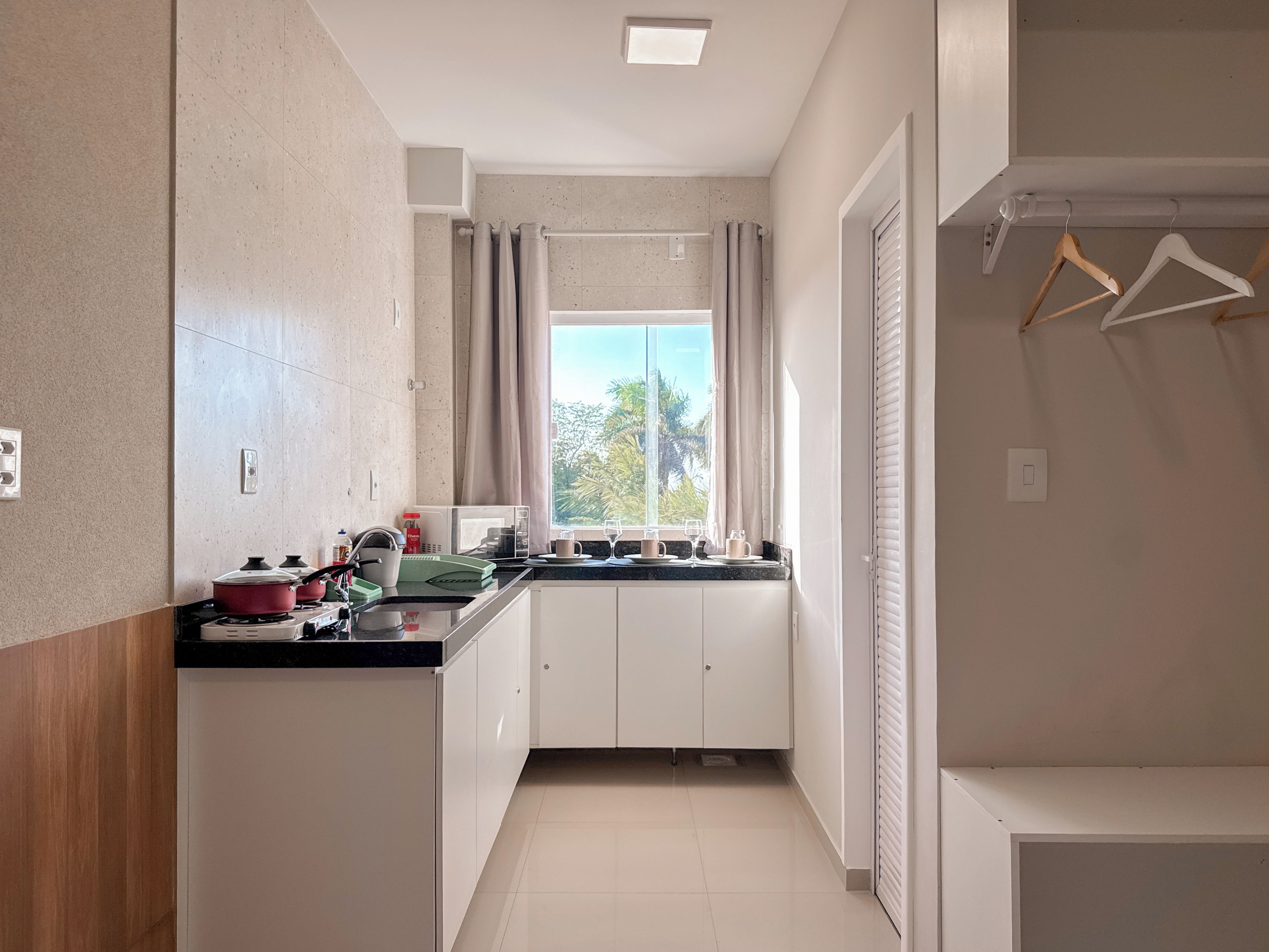Cocina moderna con ventana, armarios y encimera con diversos objetos.
