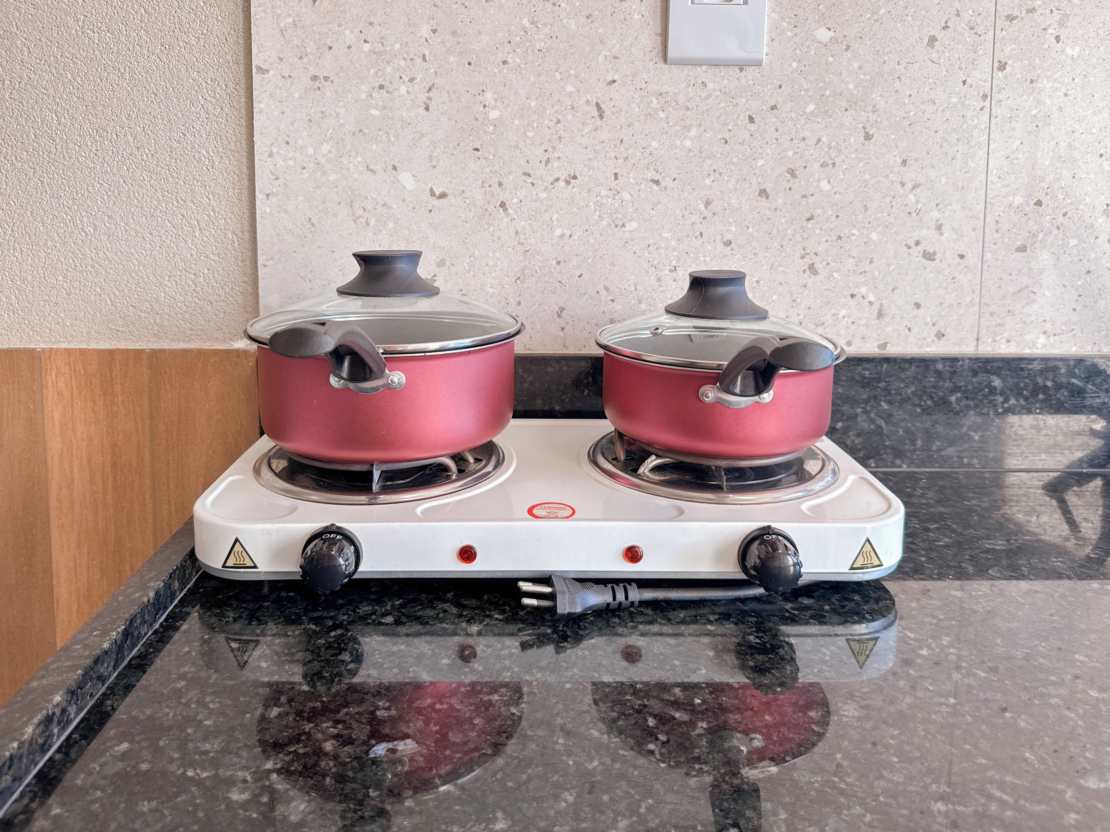 A kitchen with a white stove and two red pots on top.