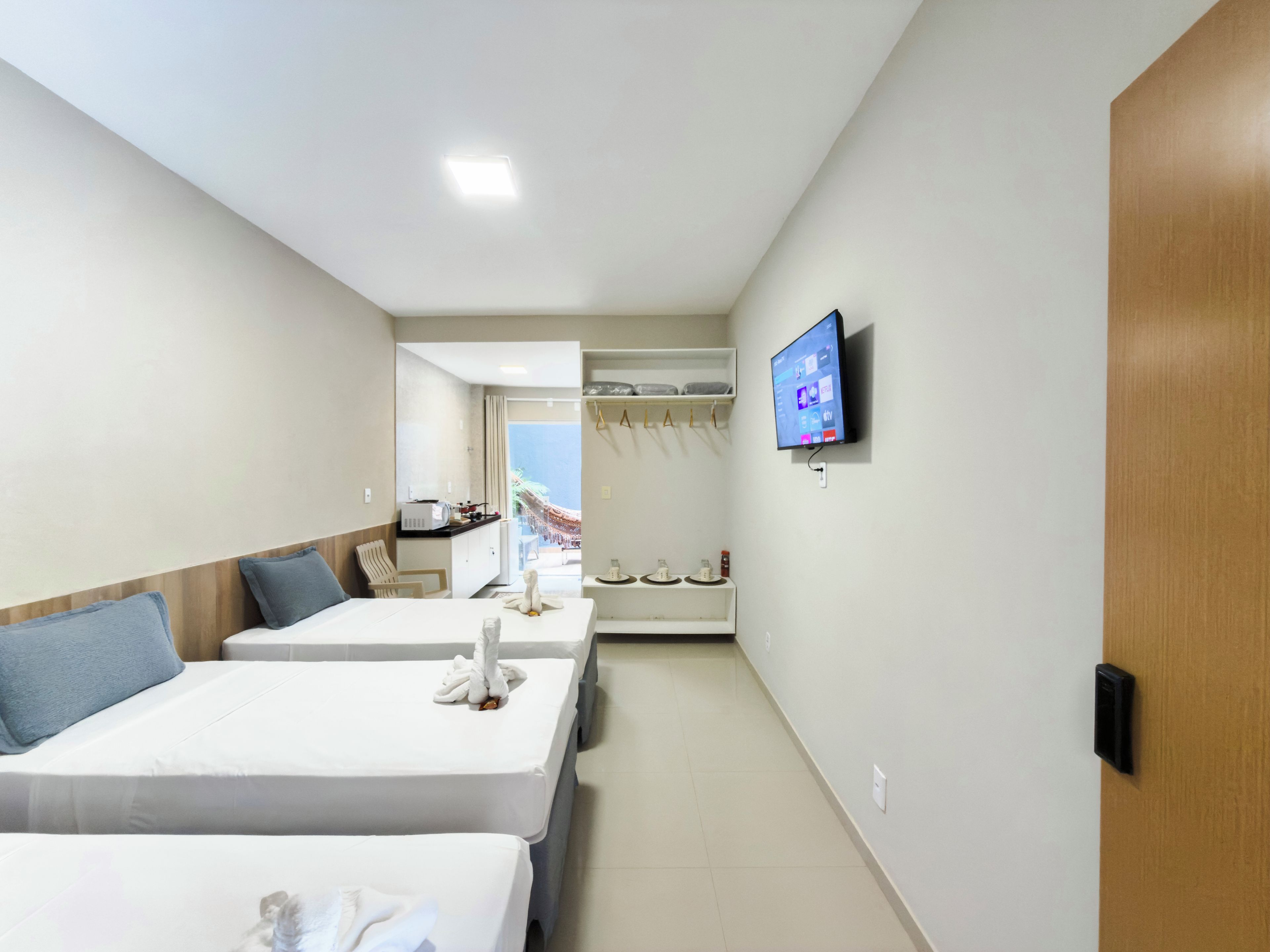 Quarto de hotel com duas camas, televisão, guarda-roupa e vista para o mar.