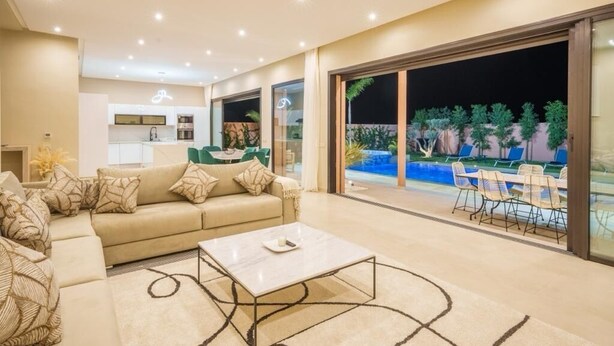 A modern living room with a sofa, coffee table, and a view of an outdoor pool area. - VILLA YASMINA ( Not overlooked, heated pool) (Marrakech)