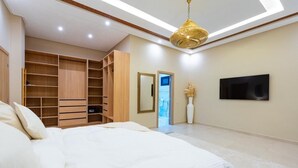 A bedroom with a large bed, built-in wooden wardrobe, a flat-screen TV, and a ceiling light fixture. - VILLA YASMINA ( Not overlooked, heated pool) (Marrakech)