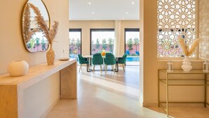 A modern dining area with a table and chairs, a decorative mirror, and a view of the outdoors. - VILLA YASMINA ( Not overlooked, heated pool) (Marrakech)