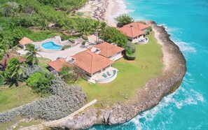 Une propriété située sur la côte, comprenant plusieurs bâtiments, une piscine et une pelouse bien entretenue.
