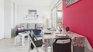 A compact living space with a dining area, a sofa, and a painting on the wall. - Apartment - balcony with view - swimming pool (Guérande)