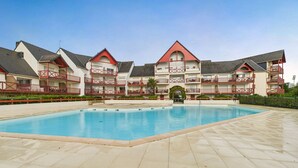 A hotel with a swimming pool, multiple balconies, and a red and white color scheme. - Apartment - balcony with view - swimming pool (Guérande)