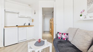 A compact living space with a kitchenette, a dining table, and a sofa. - Apartment - balcony with view - swimming pool (Guérande)