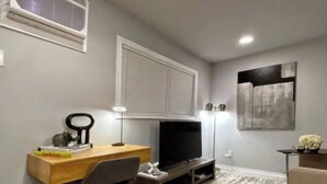 A modern living room with a flat-screen TV, wooden desk, and a comfortable chair. - Montrose Cheery Studio! Medical Center 09 ★★★★★ (Houston)