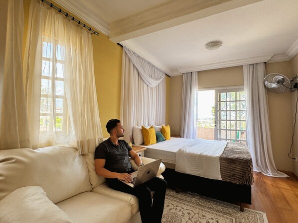 Une chambre à coucher avec un lit, un canapé et une fenêtre avec des rideaux.